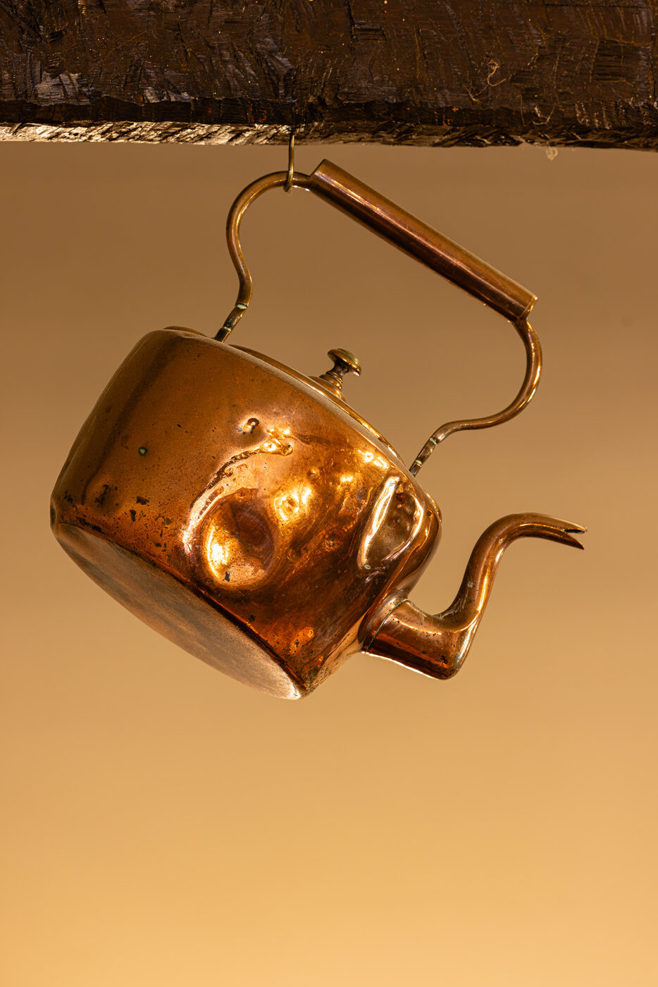 Antique copper kettle hanging from a beam in the tearoom