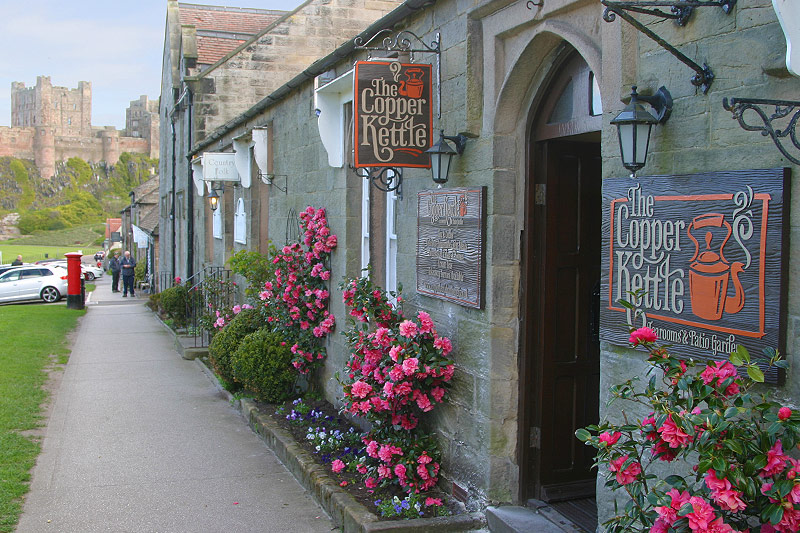 The Copper Kettle shopfront on Front Street, with Bamburgh Castle behind