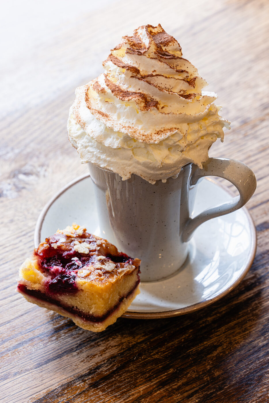 Hot chocolate topped with cream, served with a cake slice
