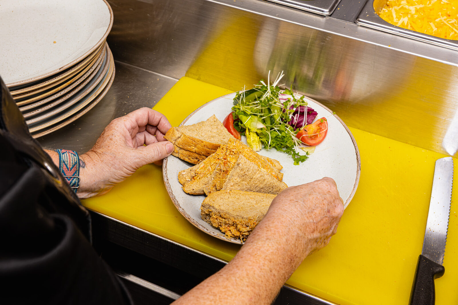 A freshly made sandwich and salad being plated in the kitchen