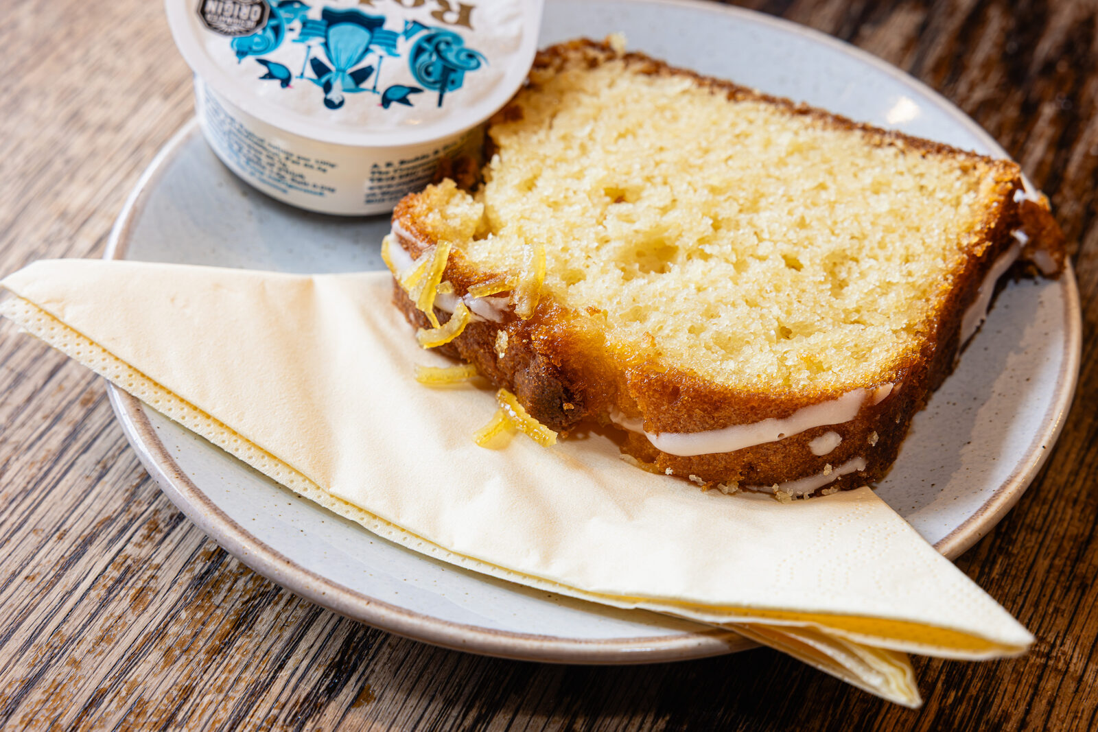 A slice of lemon drizzle loaf with a pot of clotted cream